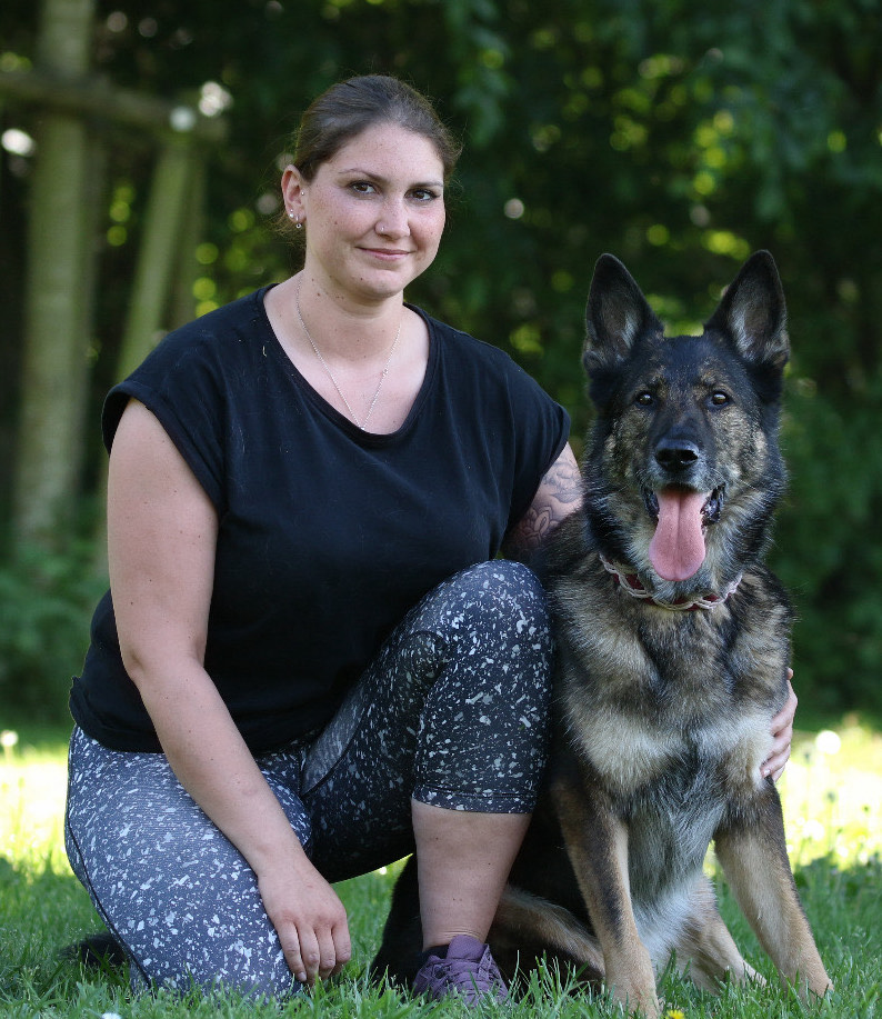 HUndephysiotherapeutin Kimberly Olszewski posiert mit Scäferhund Ferry im Wald